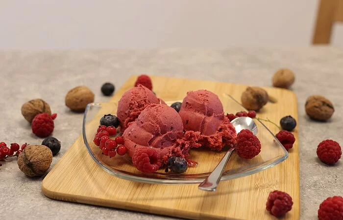 Eiskugeln drapiert auf Glasteller mit Früchten dekoriert