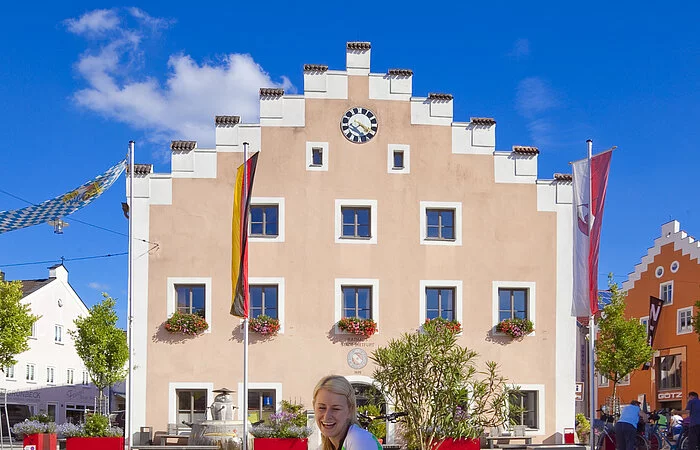 Zwei Radfahrer sitzen am Drachenbad vor dem Rathaus und erfrischen sich am Wasser