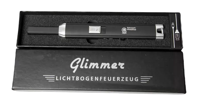 In der Schachtel liegend das Lichtbogenfeuerzeug mit aufgedruckter Naturpark-Marke. Im unteren Bildbereich liegt der Deckel der Schachtel, mit aufgedrucktem Markennamen.