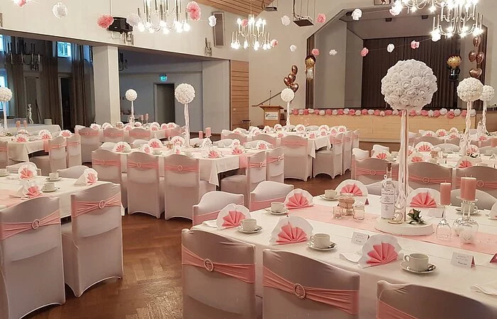 Elegante Dekoration in rosé-weiß, eingedeckt mit Kaffeegeschirr, Stühle überzogen mit Hussen in weiß, dazu Schleifen in rosé