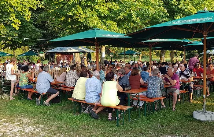 Blick von der Wiese in den Biergarten an der Stadthalle an einem sonnigen Tag.
