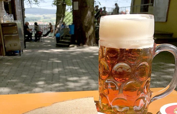 Drei Bratwürste mit Kraut und Brot auf einer Bierbank, dazu eine Maß Wettelsheimer Keller Märzen