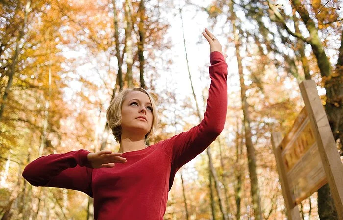 Eine Frau zeigt eine QiGong-Übung im Freien