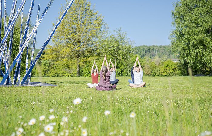 Yoga in der Gruppe im Kurpark mit Arme zum Himmel