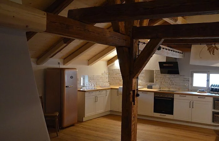 Wohnküche voll ausgestattet in weiß mit Holzplatte.