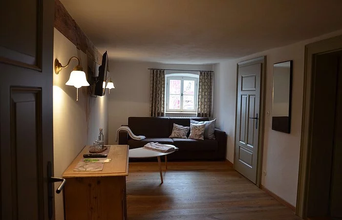 Wohnzimmer in der Gasthof Krone Kinding mit einem gemütlichen Sofa mit Beistelltisch und einem Fernsehen.