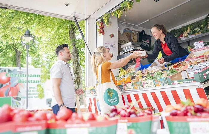 Aufnahme an einem Obst- und Gemüsestand am Treuchtlinger Wochenmarkt. Ein junges Pärchen kauft gerade ein.