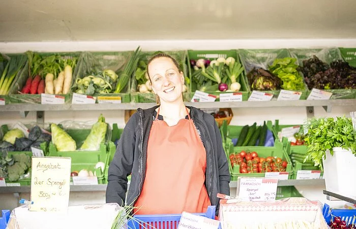Frontaufnahme einer Verkäuferin in einem Obst- und Gemüsestand am Treuchtlinger Wochenmarkt.