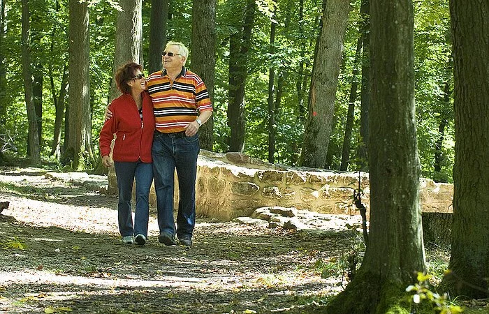 Ein älteres Eehepaar spaziert durch den Wald.