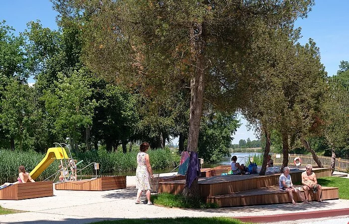 Blick auf Sitzgelegenheiten im Flussfreibad. Links im Hintergrund sieht man eine Rutsche.