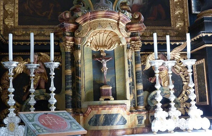 Altardetail - ein Kreuz umrahmt von Kerzen