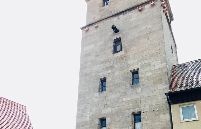 Ein hoher Stadtturm aus Stein. Durch den Turm führt ein Stadttor.