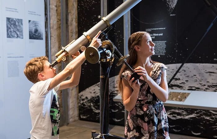 Zwei Kinder schauen durch ein Teleskop