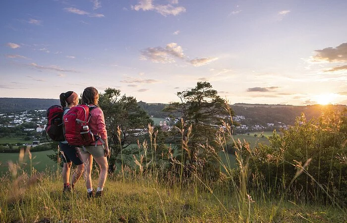 Zwei Frauen mit Wanderrucksäcken stehen am Frauenberg und genießen den Sonnenuntergang, sowie den schönen Blick über Eichstätt.