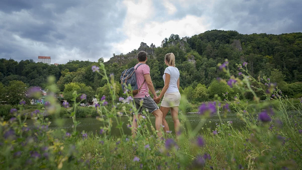 Am Main-Donau-Kanal steht ein Pärchen händchenhaltend und lässt ihren Blick aufs Wasser und auf den grünen Hängen dahinter schweifen.