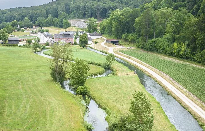 Drohnenaufnahme mit weitem Blick in das Möhrenbachtal. Der Möhrenbach mäandriert wunderschön durch die weiten Felder am Waldrand entlang.
