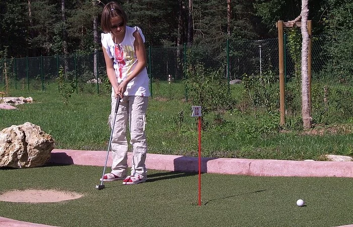 Auf dem Family Golfplatz im Seezentrum Heuberg am Rothsee spielt ein Mädchen hingebungsvoll Minigolf auf einem grünen Platz.