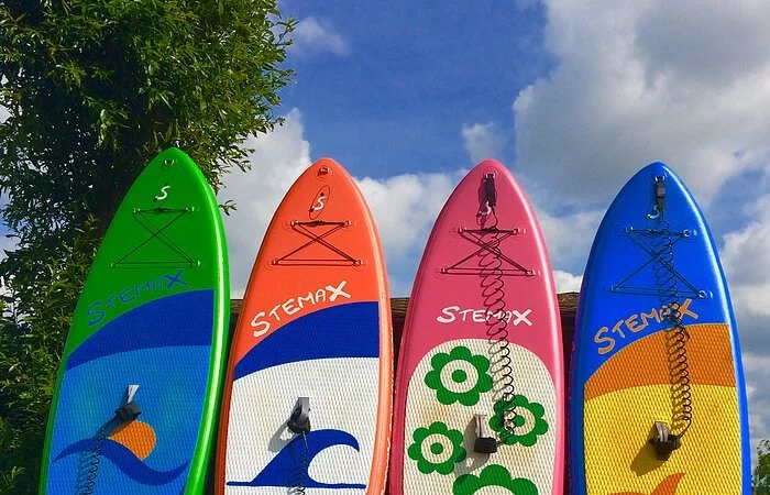 Vier Boarde unterschiedlich bedruckt lehnen an einem Zaun.