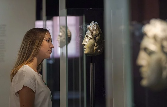Frau sieht sich die Reitermasken im Römermuseum an.