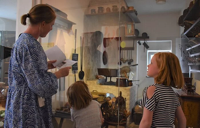 Eine Frau mit zwei Kindern sieht sich die alte Küche im Heimatmuseum an.