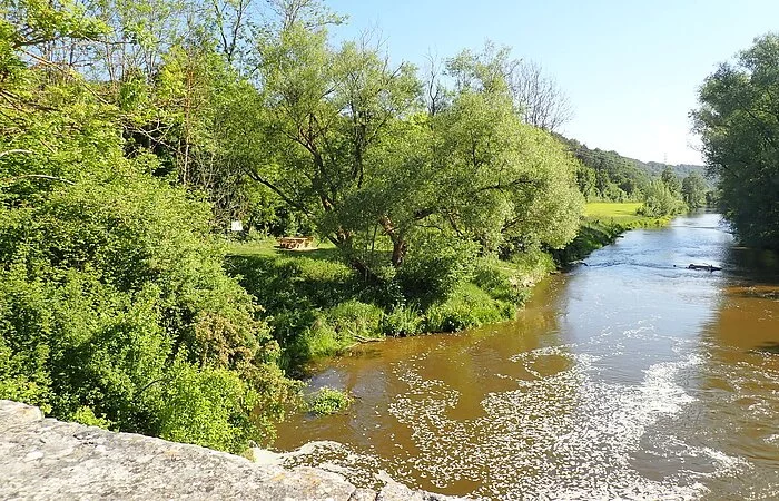 Der Bootrastplatz Pfünz ist von weitem zu sehen, etwas versteckt durch die Bäumer und Sträucher am Ufer. Er liegt unweit der steinernen Brücke direkt an der Altmühl.