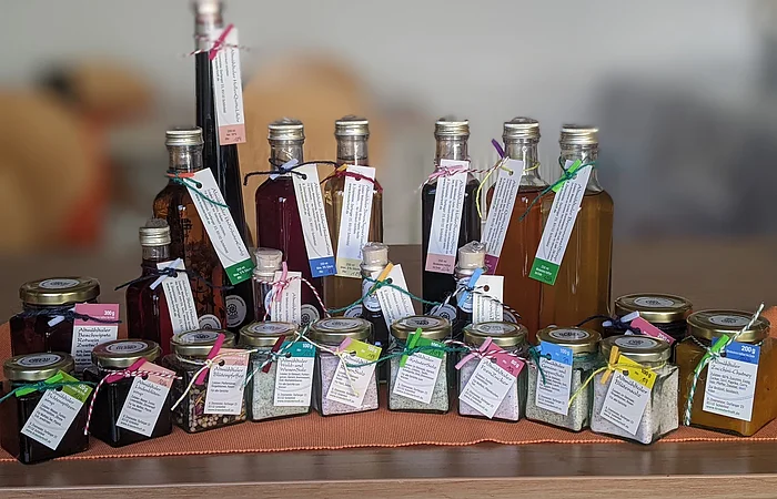 Im Halbrund arrangiert stehen verschiedene Fläschchen und kleine Gläser mit Produkten von Brigitte Zinsmeister auf einem Tisch.