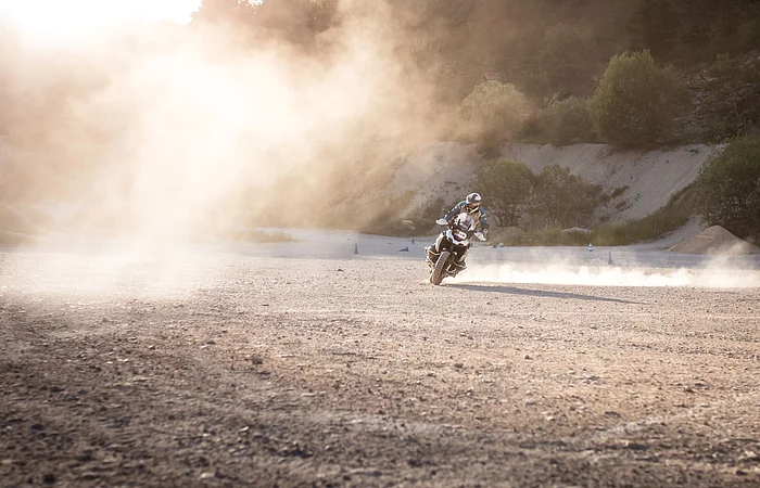 Ein Mottoradfahrer fährt über den Schotterplatz im Enduropark Heidenheim. Der Schotter staubt.