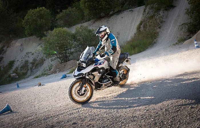 Ein Mottorradfahrer fährt über einen Schotterplatz.