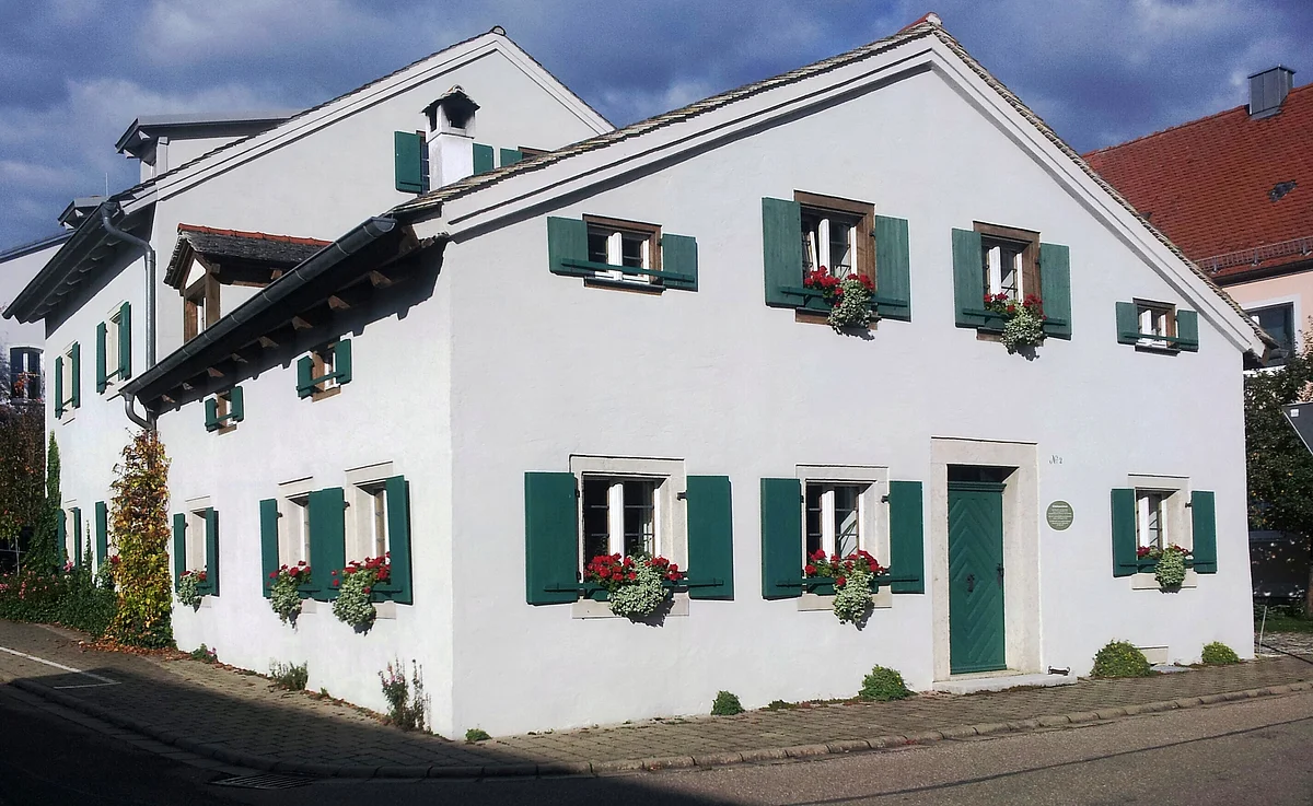 Das Jurahaus mit seinen grünen Fensterläden und Haustür ist schmuck. Die Fenstersimse zieren Blumenkästen.