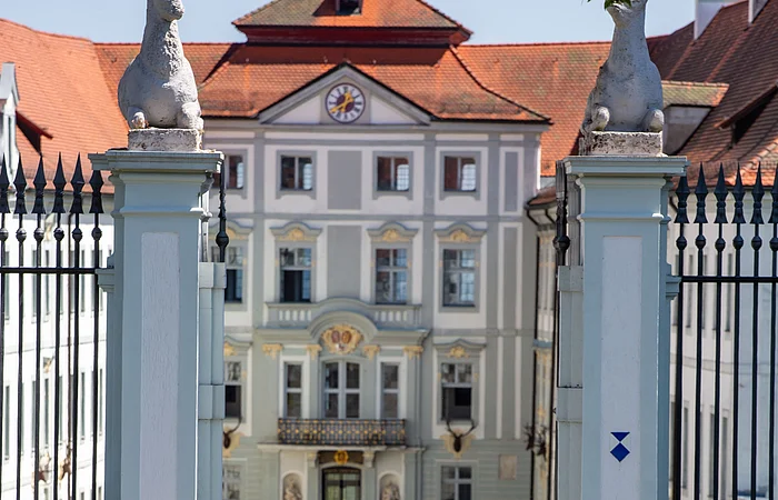 Zwei Rennradler fahren durch das Tor von Schloss Hirschberg bei Beilngries, in deren Hintergrund erkennt man den zentralen Eingang des Schlosses