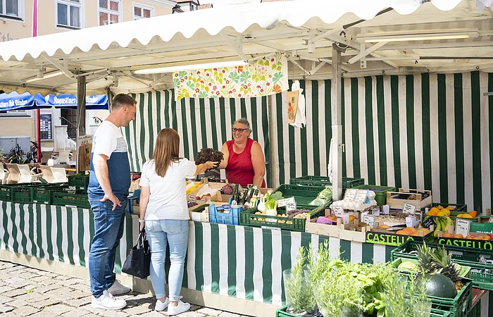 Ein Paar kauft am Wochenmarkt in Wemding bei einem Verkaufsstand ein.