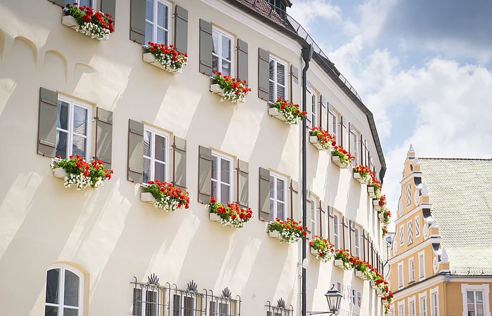 Das Verwaltungsgebäude von außen im Sommer mit Blumenkästen an den Fenstern.