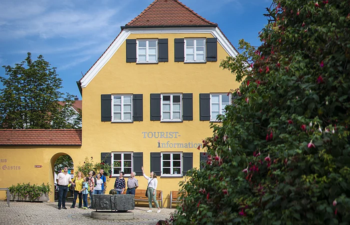 Die Stadtführerin ist mit einer Gruppe am Mangoldbrunnen vor der Tourist-Information.