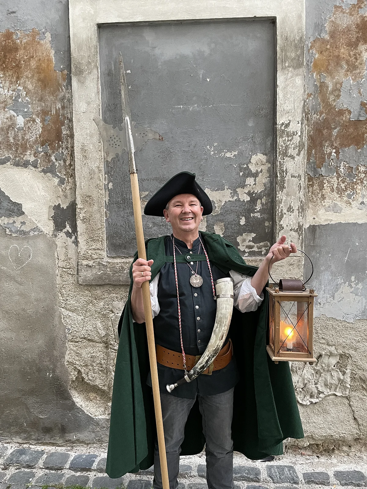 Nachtwächter im Kostüm vor verwitterter Hauswand