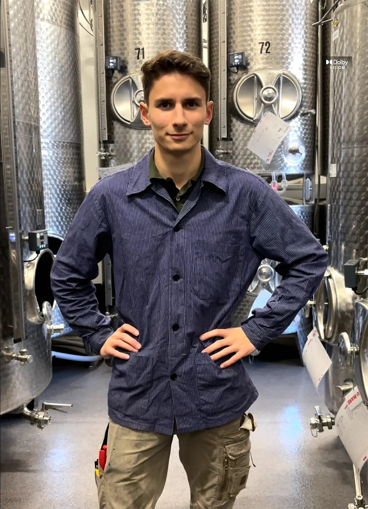 Junger Mann steht zwischen Edelstahltanks in Weinkeller