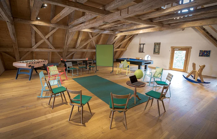 Einige Stühle die im Kreis aufgestellt sind mit einer Tafel, im Dachgeschoss.