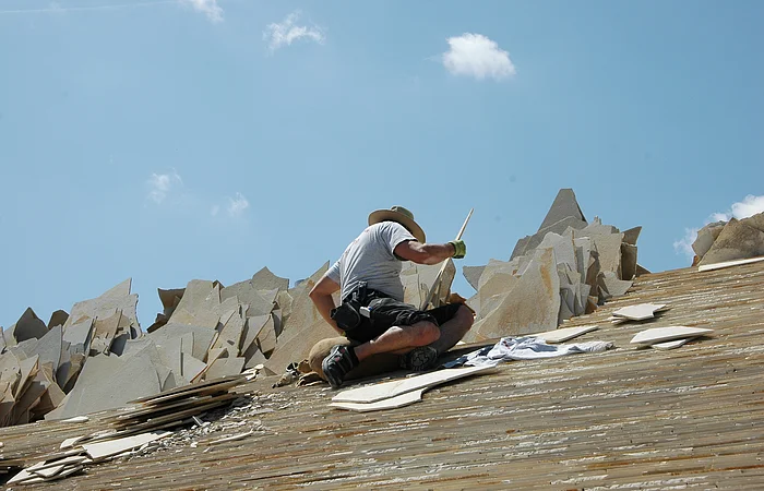 Ein Dachdecker legt die Juraplatten auf den Dachstuhl eines Jurahauses