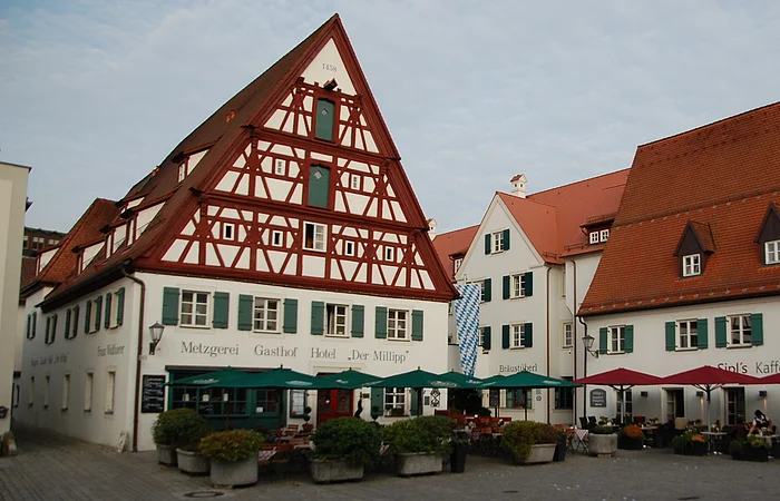 Fachwerkhaus mit grünen Fensterläden und Biergarten davor.