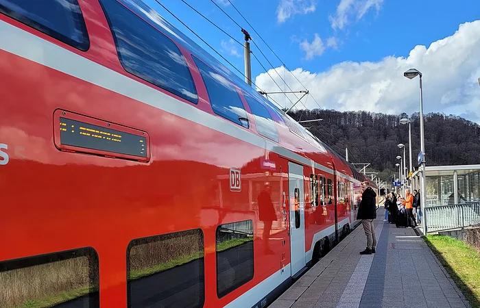 Eine Regionalbahn hat am Gleis gehalten und Reisende warten darauf, dass sich die Türen öffnen.