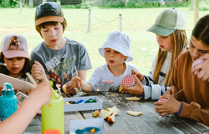 An einem Tisch basteln und Malen sechs Kinder sehr konzentriert Ihre Sachen.
