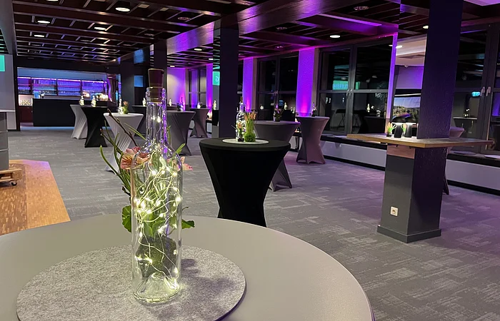 Die schwarzen und grauen Stehtische sind im Raum verteilt. Unterschiedliche Lichtquellen schaffen eine harmonische Atmosphäre.