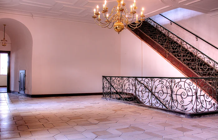 An den kahlen Wänden führt eine Treppe mit aufwändigen Details nach unten.