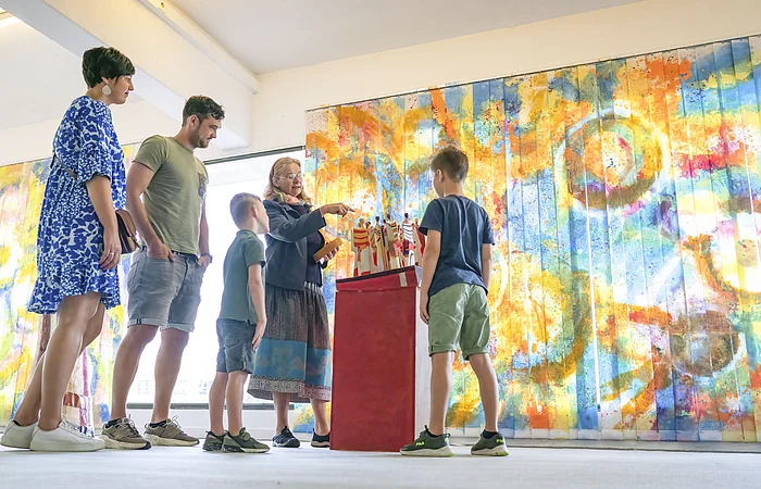 Eine Familie sieht sich im KunstMuseum ein Kunstwerk an.