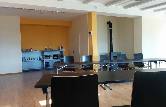 Die schwarzen Stühle stehen vor einer orangenen Wand im Raum verteilt.