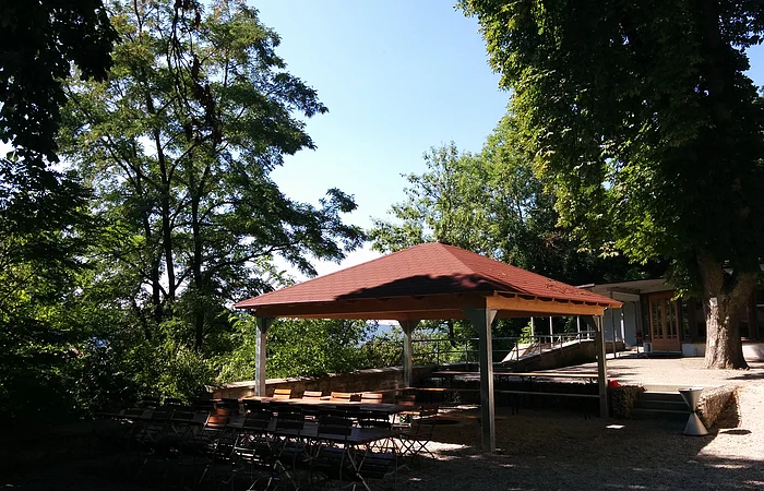 Der Pavillon ist draußen im Schatten, mit Holzmöbeln platziert.
