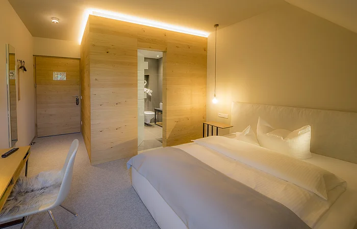 Die natürliche, hölzerne Einrichtung mit einem großen Einzelbett ist sehr hell gestaltet.