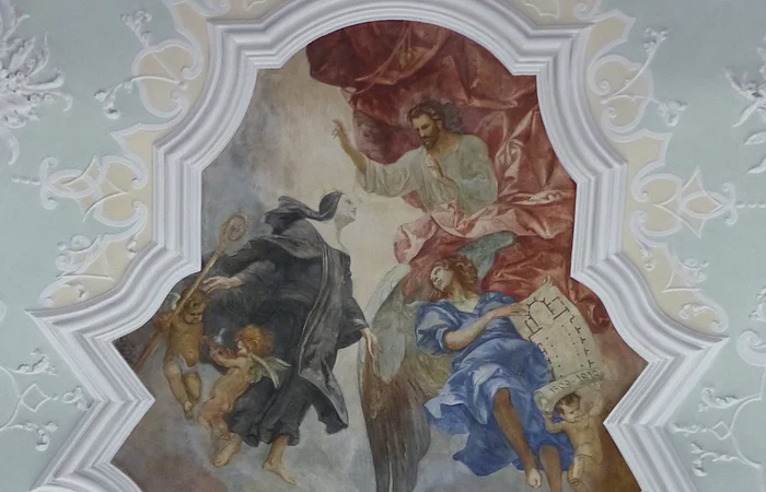 Deckenfresko mit religiösen Figuren, darunter Engel und Heilige, die über einer Landschaft mit Gebäuden, der Stadt Monheim schweben.