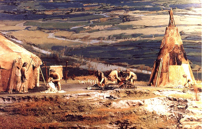 Miniaturmodell einer prähistorischen Siedlung mit Menschen, die um Zelte aus Tierhäuten arbeiten.