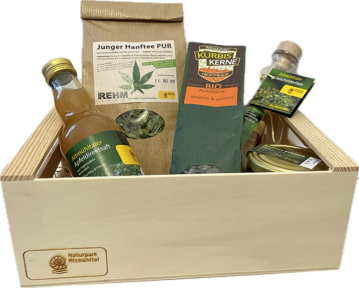 Holzkiste mit verschiedenen regionalen Produkten: Apfelsaft, Hanftee, Kürbiskerne, Wacholderlikör und Honig.