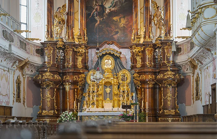Barocker Kirchenaltar mit reich verzierten goldenen Elementen und Gemälde im Hintergrund.
